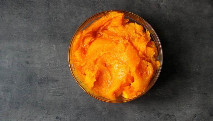 Healthy cooked pumpkin puree in a round bowl on a dark background